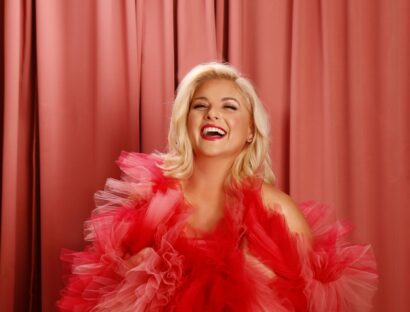 Lucy Durack posed laughing in a pink and red tulle dress.